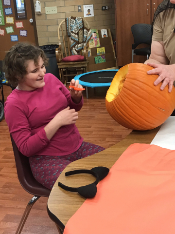child scooping out pumpkin guts